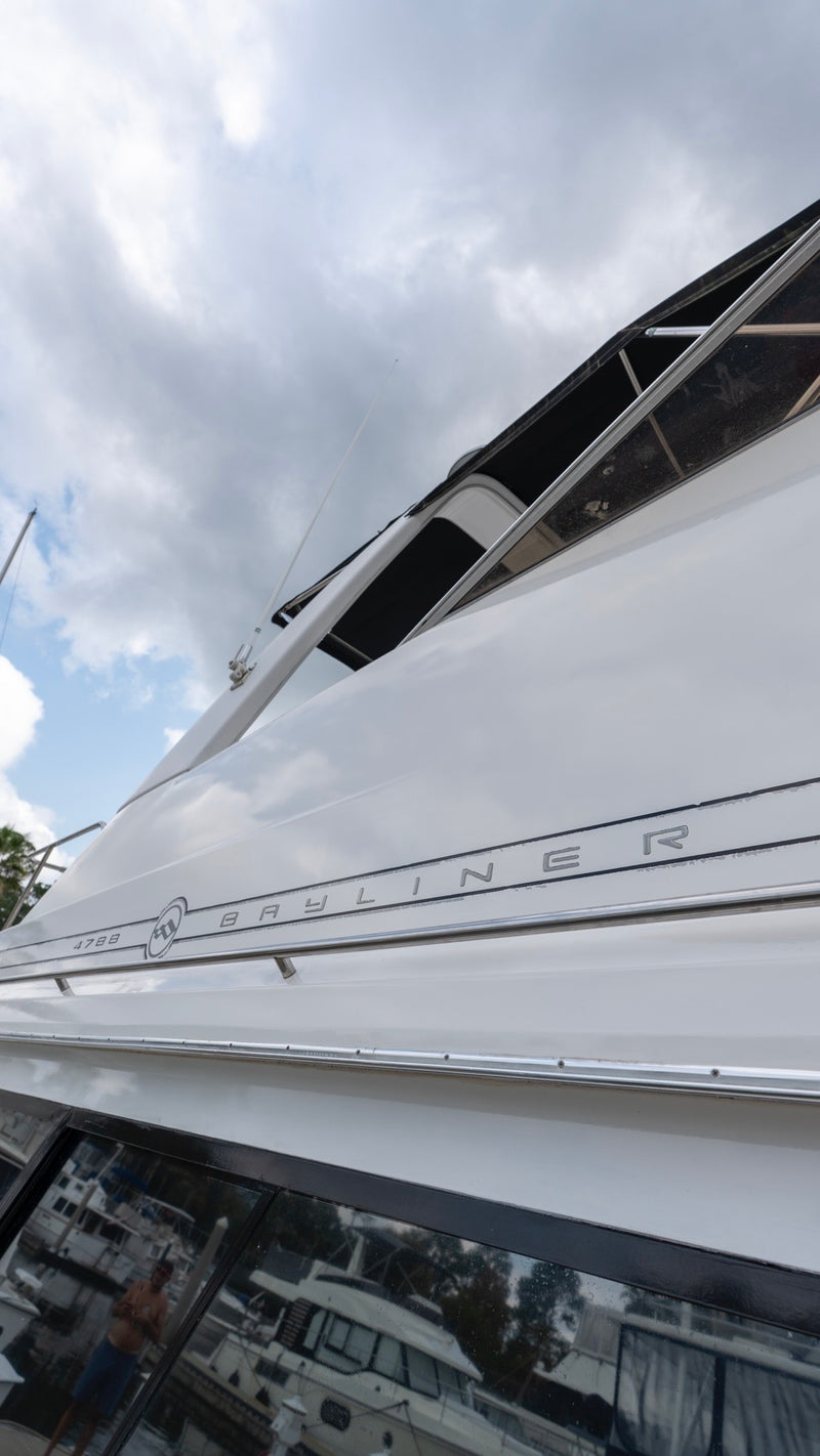 Close-up of a white Bayliner 4788 boat hull showing a glossy, mirror-like gelcoat finish after Re-Gel restoration.