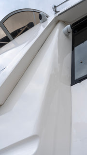 Close-up of a white Bayliner 4788 boat hull showing a glossy, mirror-like gelcoat finish after Re-Gel restoration.